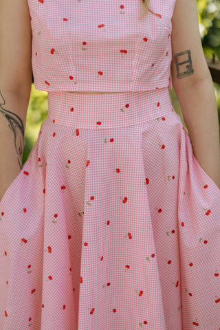 Close-up of the Lolita Skirt by Cori Tailor, showing high waistband and pink gingham fabric with cherry print, paired with matching crop top