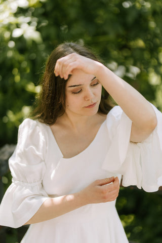 Model wearing the Freya Dress by Cori Tailor with soft puff sleeves, photographed in natural light with a serene expression