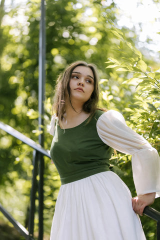 Close-up of the Heidi Dress showing green fitted bodice and white puffed sleeves, outdoor shot with soft natural light.